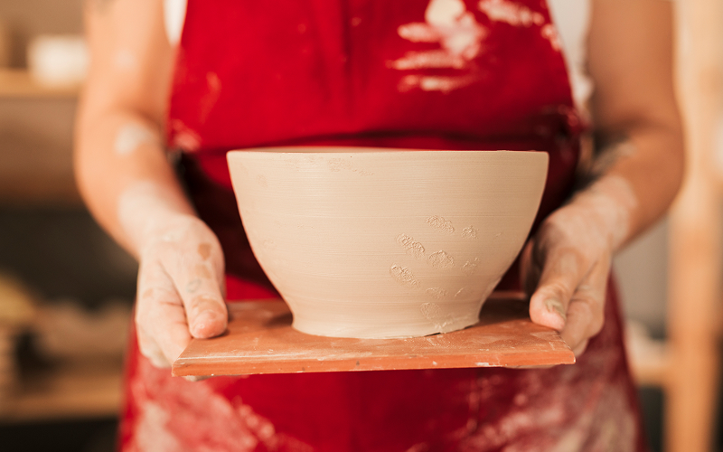 A pair of hands holding a handmade ceramic bowl