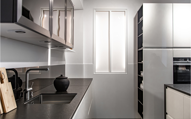 A sleek white galley kitchen with integrated appliances and open shelving