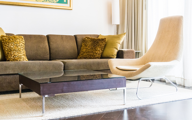 A slim-legged sofa and glass coffee table arranged in a compact condo living area