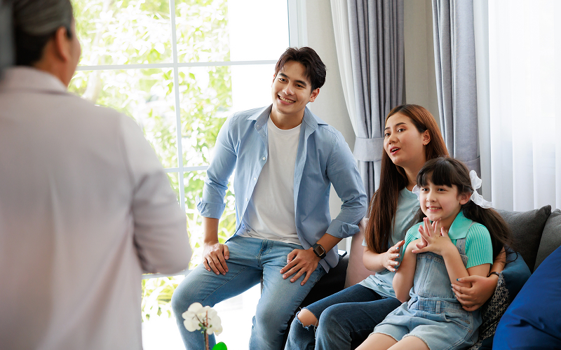 A family of grandparents, parents, teenagers, and young children interacting naturally in a living room.